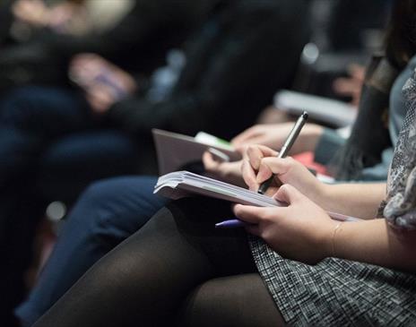 People taking notes at a lecture