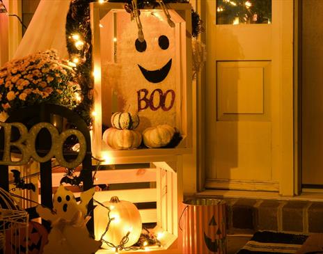 Small display of ghosts and white pumpkins with orange lights