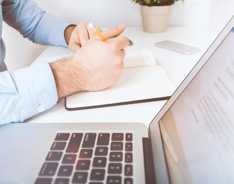 White laptop and man writing in notebook