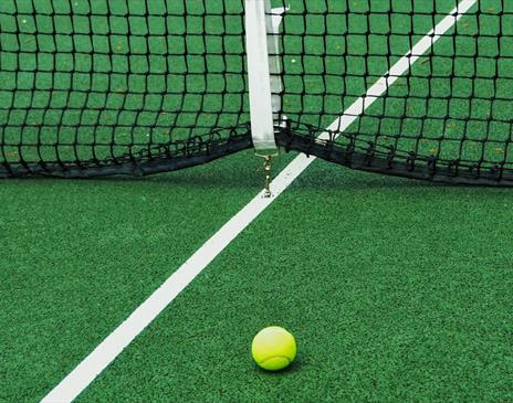 Yellow ball on green tennis court