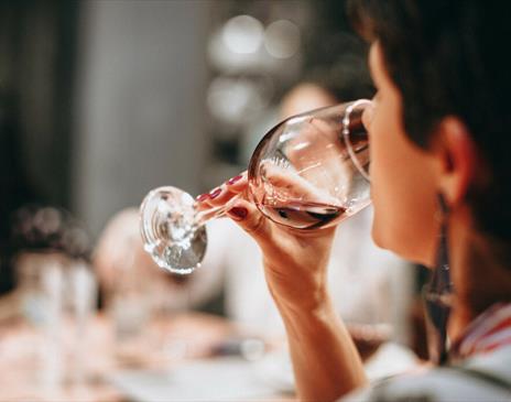 A person drinking from a clear wine glass