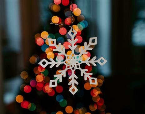 White wooden snowflake decoration lit up by multi-coloured lights