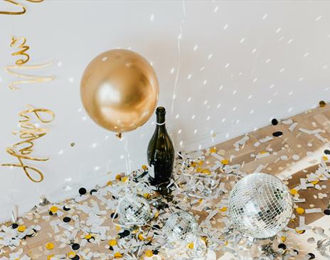 Golden confetti and disco balls with champagne bottle on the floor