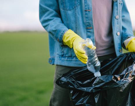 Yellow gloves placing a bottle in a bag