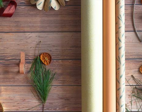 Neutral wrapping paper with Christmas tree branches and gold scissors