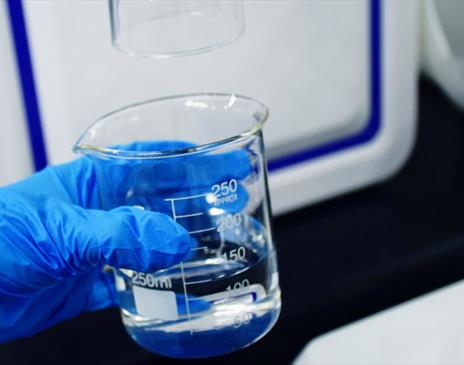 Blue glove holding glass beaker