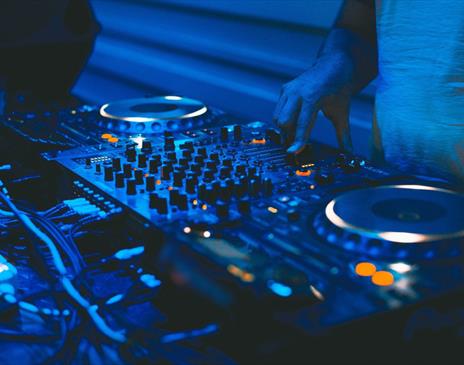 DJ and mixing decks in a blue light