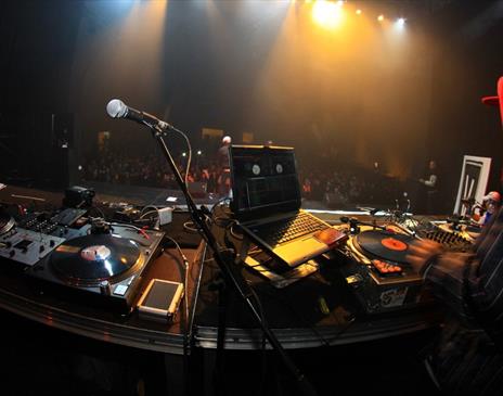 Person in a red hood DJing to a large crowd