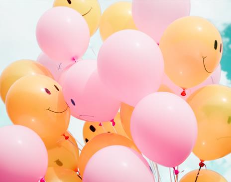 Yellow and pink balloons against a blue sky
