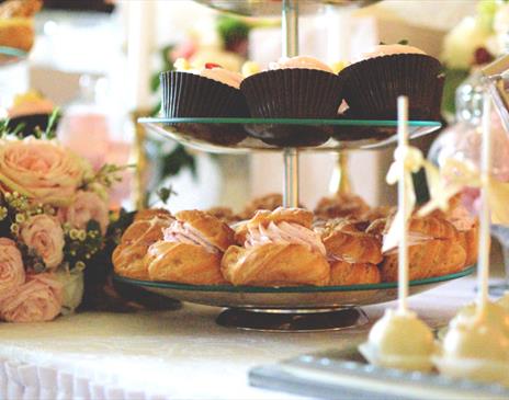 Cupcakes on stand with pink roses and small cakes beside them