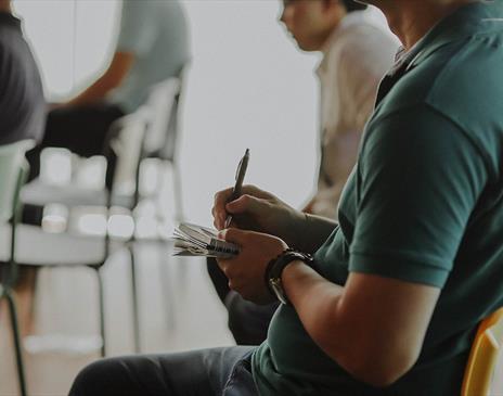 Person sitting in a chair taking notes on paper