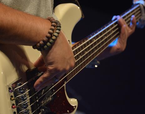 Person playing a white electric guitar