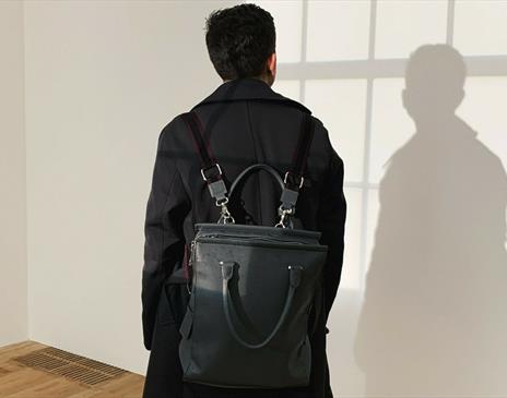 Person with black backpack and dark jacket looking at wall