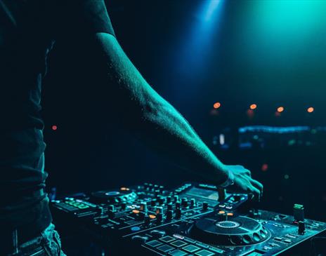 DJ working mixing decks in a green light