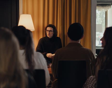 Long haired individual talking to a crowd