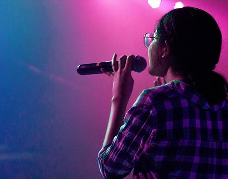 Woman onstage holding a microphone