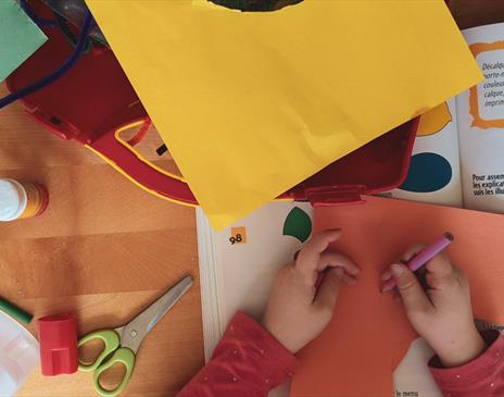 A child surrounded by bright cardboard at a craft table