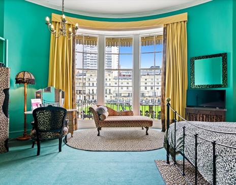 Betties Boudoir room at Hotel Pelirocco showing a green room with a leopard print bedcover and wall hangings.