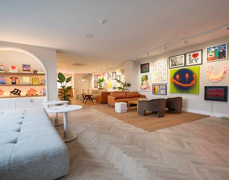 Inside the gallery at Helm, showing comfortable sofas and vibrant artwork int he background