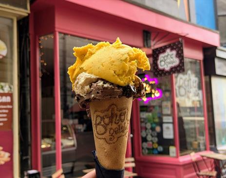 An ice cream cone being held up in front of the Boho Gelato store