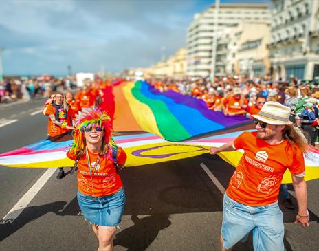 Image courtesy of Jim Carey. Pride revelers carrying a large Pride flag through the streets of Brighton to mark the start of the parade.