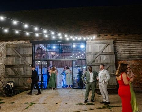 Guests enjoying a party night at Charleston. Image shows guests stood outside the haybarn at Charleston