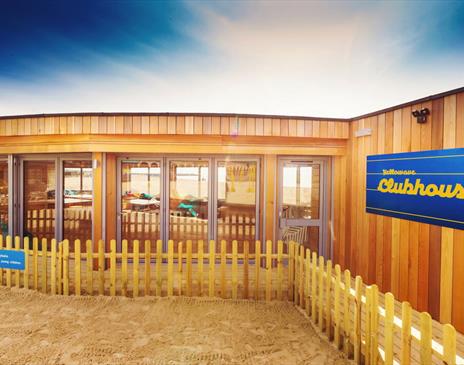 Outside shot of the Yellowave Beach House, a wooden structure with sand outside.