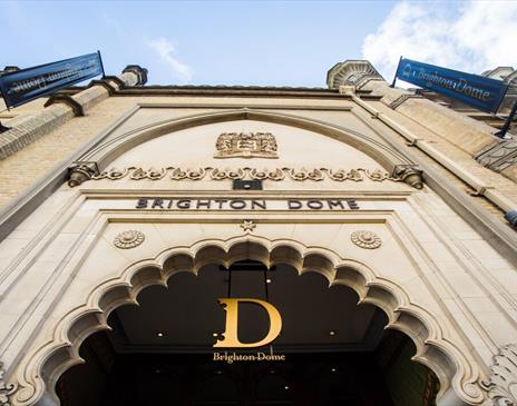 The exterior main entrance of Brighton Dome, the shot is taken looking up toward the Dome sign above an intricate doorway.