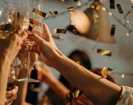 Image shows guests celebrating at a Private Christmas party at DoubleTree by Hilton Brighton Metropole. Champagne flutes are raised in the air whilst