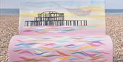 Bench sculpture on the pebbles painted with an image of Brighton' West Pier