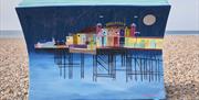 Bench sculpture on the pebbles painted with an image of Brighton Palace Pier at night