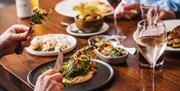 Diners tucking into small plates with white wine.