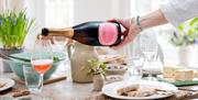 A bottle of wine being poured into a glass at a dinner table.