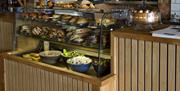 Inside the cafe showing a counter with sandwiches and bagels on display.