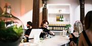 A lady at a bar is pouring a drink into a glass