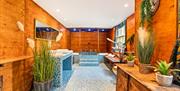 The huge luxurious bathroom as part of the Botanic Room suite, steps up to a sunken bath have been tiled in blue and white. Plants sit on the sides le