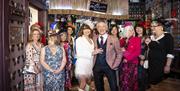 A smiling wedding group stand in a group at the Hotel Pelirocco