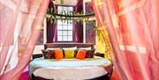 The huge circular bed in the Botanica room, set with pillows and peach coloured drapes around it.