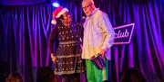 Komedia Christmas Party - Image shows the comedian Jeff Innocent on stage, a person wearing a Santa hat stands next to him.