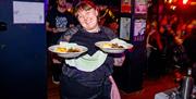 Komedia Christmas Party - a member of staff holding out two plates of delicious looking food