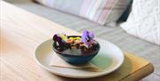 A bowl of chocolate pudding topped with bright flowers.