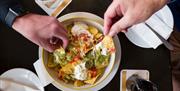 An aerial view of a group of people sharing a bowl of nachos.