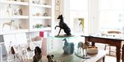 A white room with sculptures of dogs on the table and shelves. Photo credit: Syl Ojalla