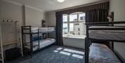 Two bunk beds sit in an airy room with gorgeous heavy grey curtains.
