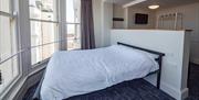 A comfy bed next to a brightly lit window.