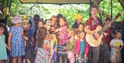 Children on a stage singing with Al Start who is playing the guitar.