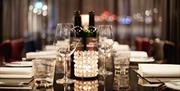 Close up of wine bottles and glasses on a table set up for a group