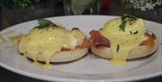 Poached eggs smothered in Hollandaise sauce atop a muffin.