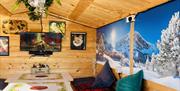 Inside Brighton Music Hall's ski chalets, full of Alpine style. Images shows inside a pine ski chalet, with an image of ski slopes behind a festive se