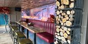 Inside Brighton Music Hall - Image shows a bar with red seating, in the foreground on the right of the bar are some logs.
